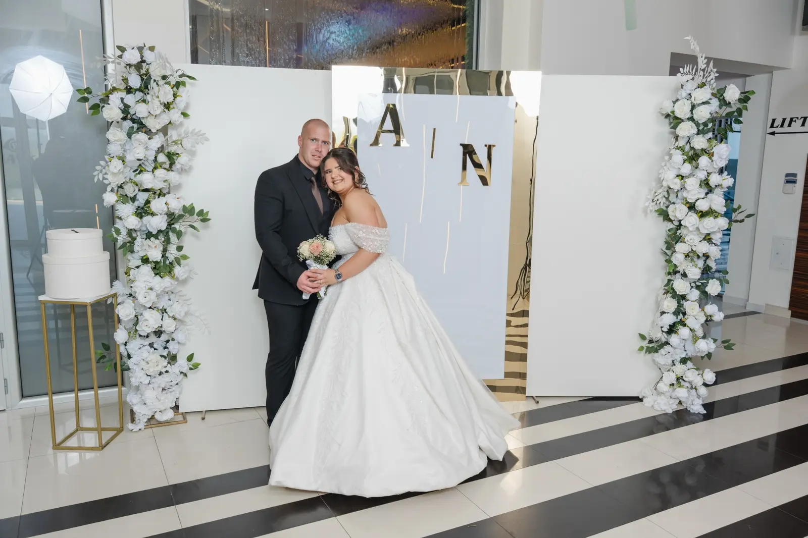 Bela cvetna foto-zona sa zlatnim ogledalom i inicijalima mladenaca u Hotelu Bavka u Leskovcu